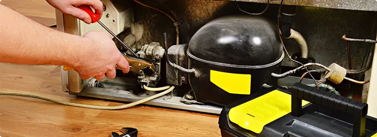Refrigerator repair technician fixing the compressor and wiring in Bainbridge Island, WA