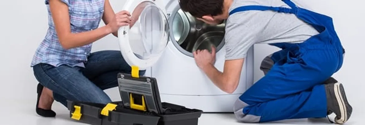 Washer repair technician inspecting a front-load washing machine with tools in Seattle, WA