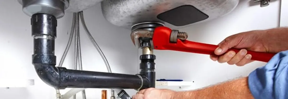 Garbage disposal repair technician tightening the sink drain and disposal connection in Seattle, WA