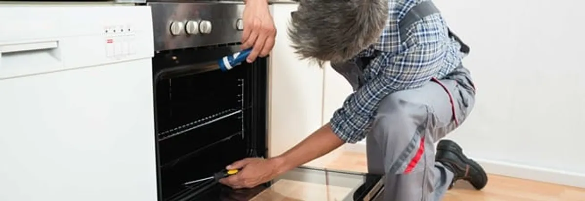 Oven repair technician inspecting and servicing an electric oven in Seattle, WA